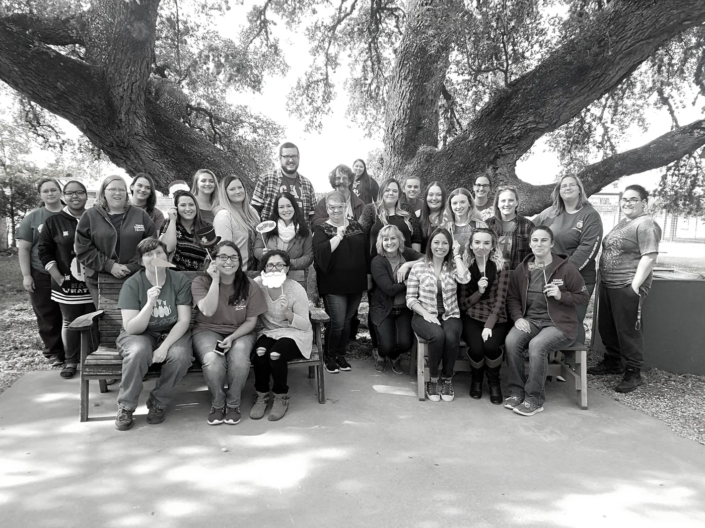 A large team gathered outdoors under an oak tree